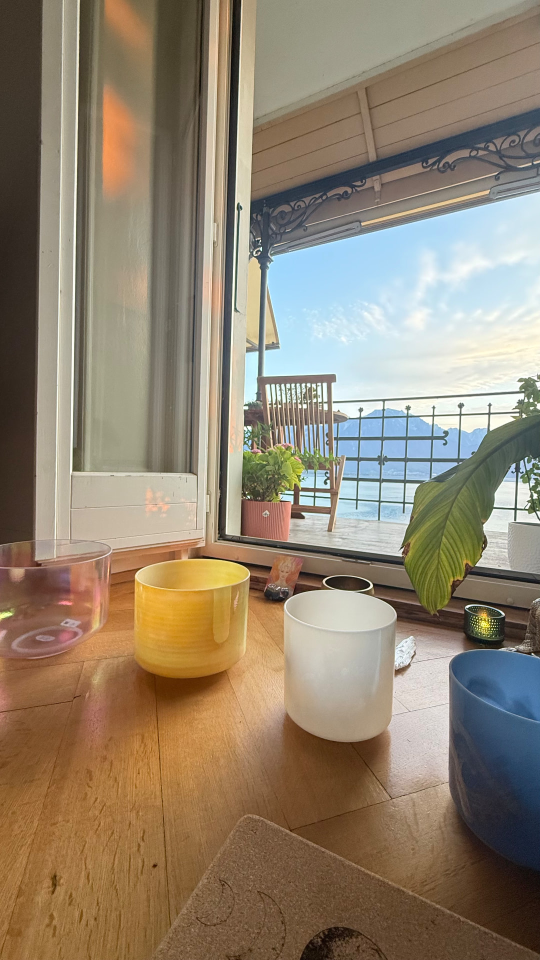 Crystal singing bowls on the parquet floor with the lake beyond the window