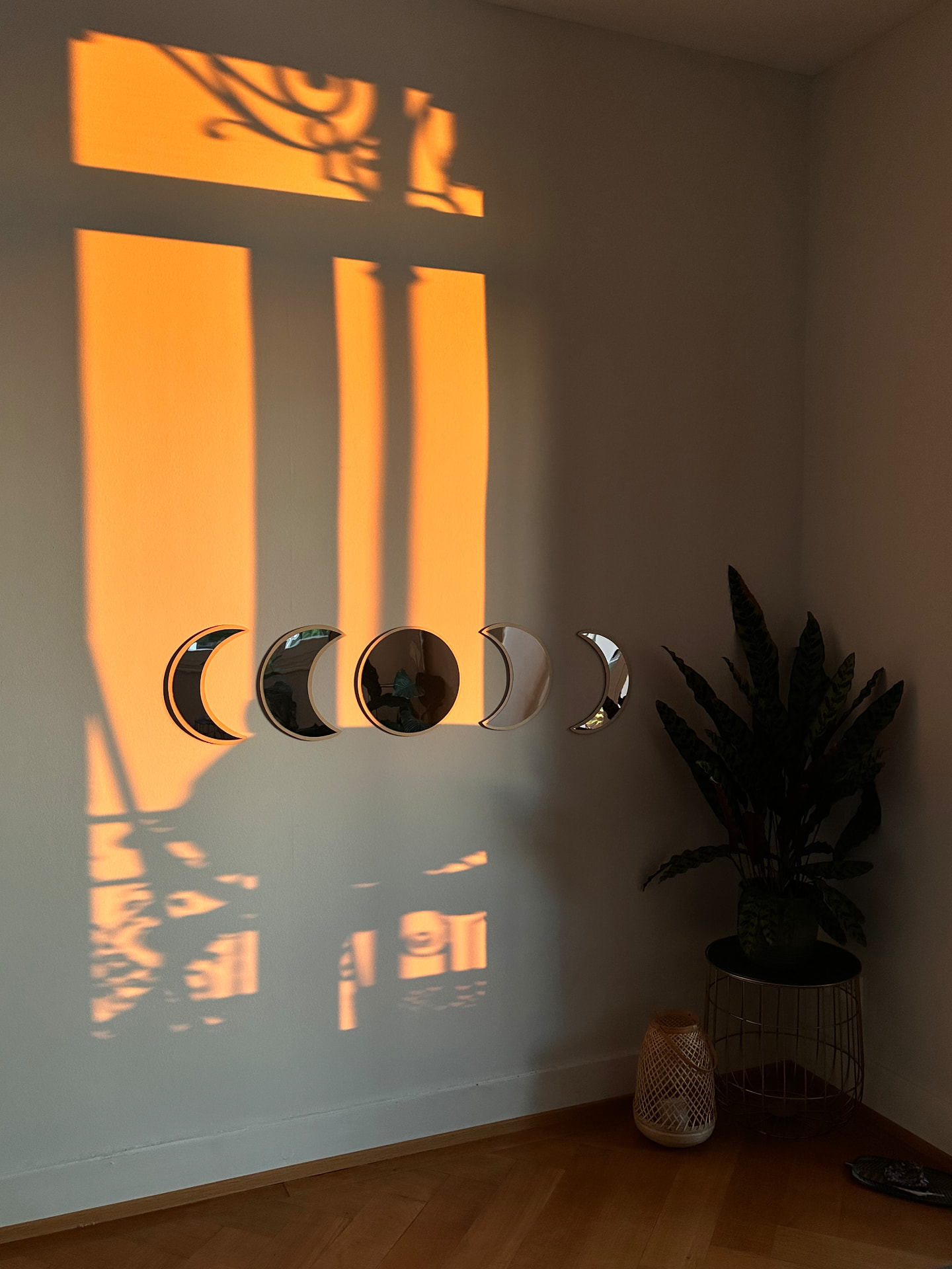 Moon phase mirrors on the wall catching warm golden sunset light