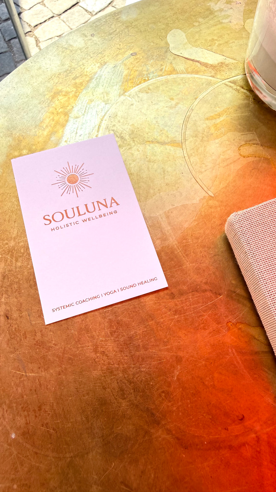 The Souluna business card resting on a sunlit copper table